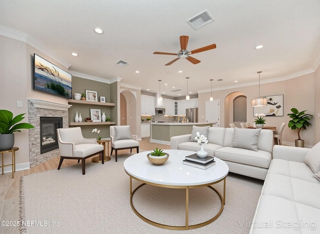 1356 Barrington Cir, Saint Augustine, FL 32092 - living area with arched walkways, a ceiling fan, recessed lighting, ornamental molding, and a stone fireplace