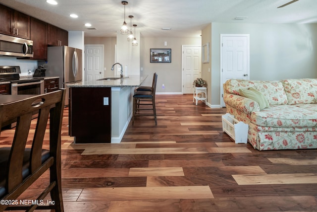 210 N Saint Clair St, Starke, FL 32091 - kitchen with appliances with stainless steel finishes, dark wood-style flooring, a breakfast bar area, light stone countertops, and dark brown cabinets