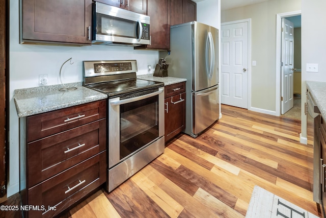 210 N Saint Clair St, Starke, FL 32091 - kitchen featuring stainless steel appliances, light wood-style floors, dark brown cabinets, and light stone countertops