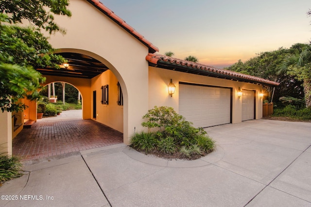 1185 Ponte Vedra Blvd, Ponte Vedra Beach, FL 32082 - property exterior at dusk with driveway, stucco siding, an attached garage, and a tiled roof