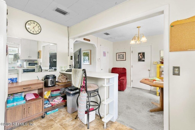 2305 Broward Rd, Jacksonville, FL 32218 - kitchen with a chandelier, white microwave, a breakfast bar area, and white cabinetry