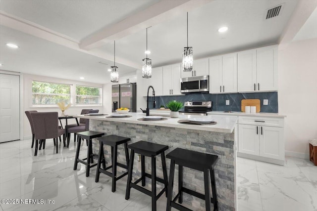 8940 Monroe Ave, Jacksonville, FL 32208 - kitchen featuring appliances with stainless steel finishes, light marble finish floors, backsplash, white cabinetry, and recessed lighting