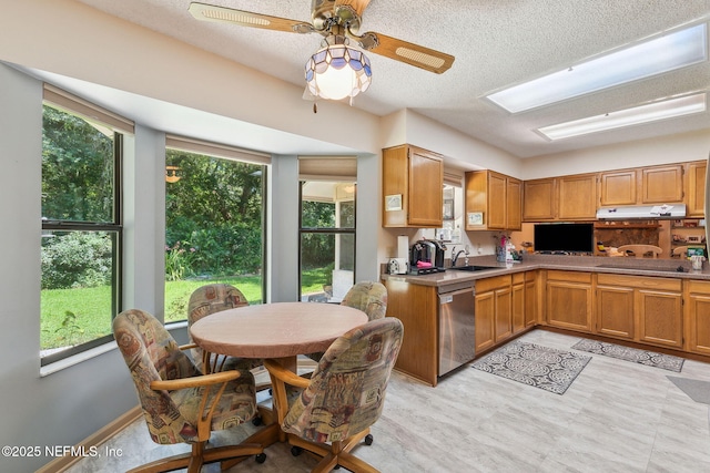 835 Fountain Dr, Fernandina Beach, FL 32034 - kitchen with stainless steel dishwasher, ceiling fan, black electric cooktop, under cabinet range hood, and light countertops