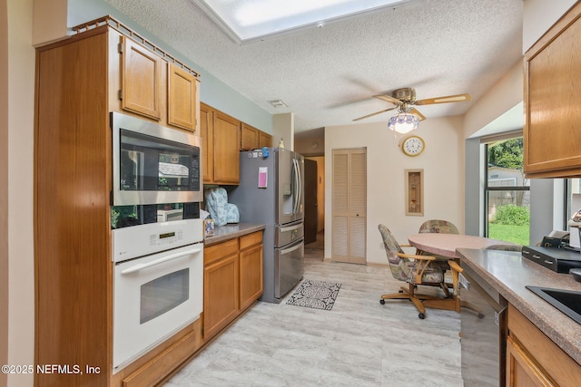 835 Fountain Dr, Fernandina Beach, FL 32034 - kitchen with stainless steel appliances, a textured ceiling, ceiling fan, and brown cabinets