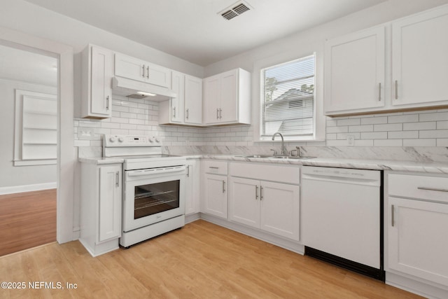 4723 Sunderland Rd, Jacksonville, FL 32210 - kitchen with white appliances, under cabinet range hood, light countertops, white cabinets, and tasteful backsplash
