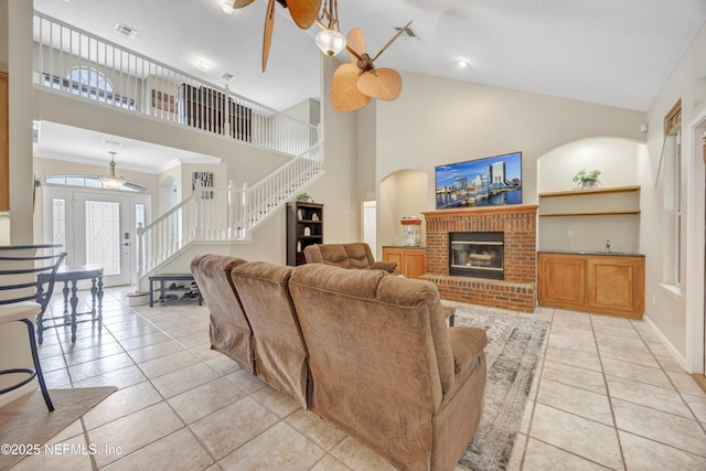 2502 Willow Creek Dr, Fleming Island, FL 32003 - living area featuring stairs, high vaulted ceiling, light tile patterned floors, a fireplace, and a ceiling fan