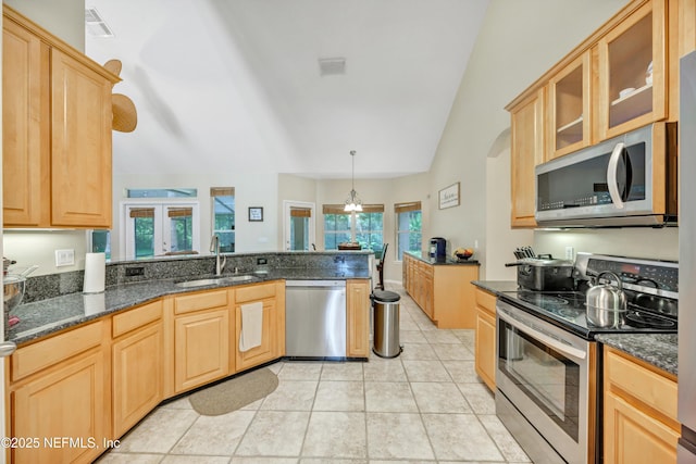 2502 Willow Creek Dr, Fleming Island, FL 32003 - kitchen with appliances with stainless steel finishes, light brown cabinetry, lofted ceiling, glass insert cabinets, and dark stone countertops