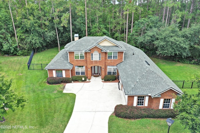 2502 Willow Creek Dr, Fleming Island, FL 32003 - view of front facade featuring brick siding, a chimney, driveway, a shingled roof, and a forest view