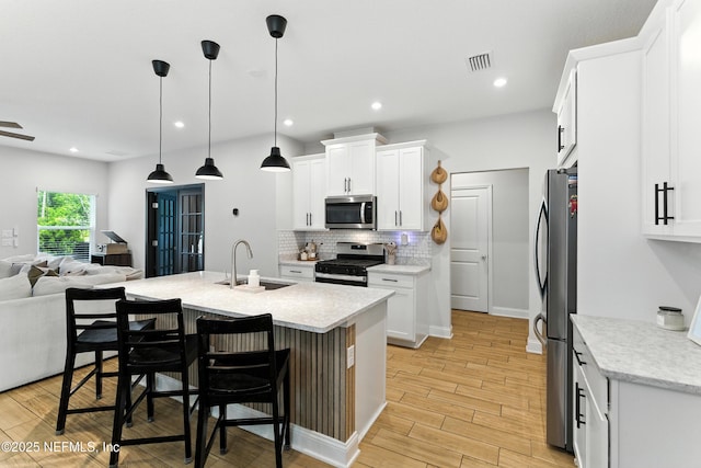 133 Wambaw Dr, Saint Johns, FL 32259 - kitchen featuring stainless steel appliances, open floor plan, backsplash, light wood finished floors, and white cabinets