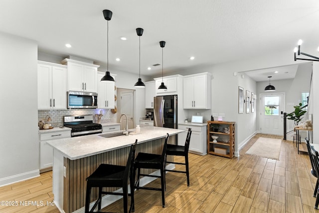 133 Wambaw Dr, Saint Johns, FL 32259 - kitchen featuring stainless steel appliances, light countertops, backsplash, light wood-style floors, and a breakfast bar