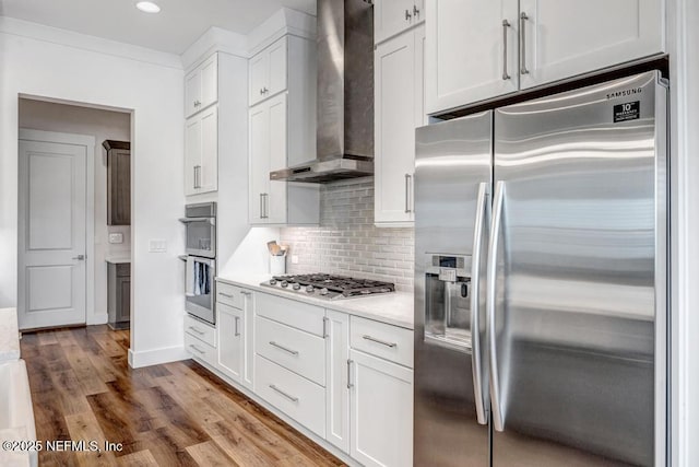 246 Glenneyre Cir, Saint Augustine, FL 32092 - kitchen featuring appliances with stainless steel finishes, wall chimney exhaust hood, light countertops, decorative backsplash, and white cabinets