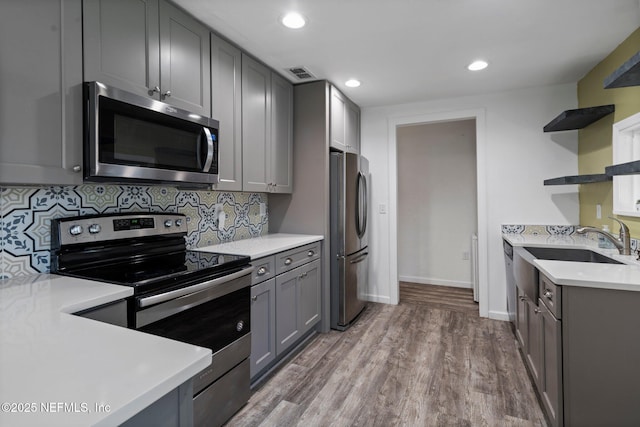 5834 Harris Ave, Jacksonville, FL 32211 - kitchen featuring stainless steel appliances, open shelves, gray cabinetry, light countertops, and wood finished floors