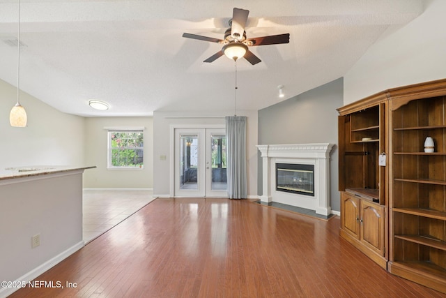 1835 Harbor Island Dr, Fleming Island, FL 32003 - unfurnished living room with a ceiling fan, vaulted ceiling, wood finished floors, a glass covered fireplace, and french doors