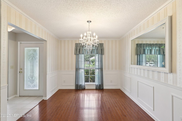 1835 Harbor Island Dr, Fleming Island, FL 32003 - unfurnished dining area with wallpapered walls, a wainscoted wall, a textured ceiling, a chandelier, and wood-type flooring