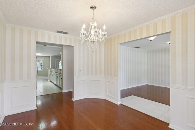 1835 Harbor Island Dr, Fleming Island, FL 32003 - unfurnished dining area with wainscoting, wood finished floors, a chandelier, ornamental molding, and wallpapered walls