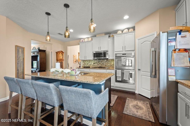 141 Mediterra Ave, Ponte Vedra, FL 32081 - kitchen featuring stainless steel appliances, tasteful backsplash, light stone counters, dark wood-style floors, and a breakfast bar