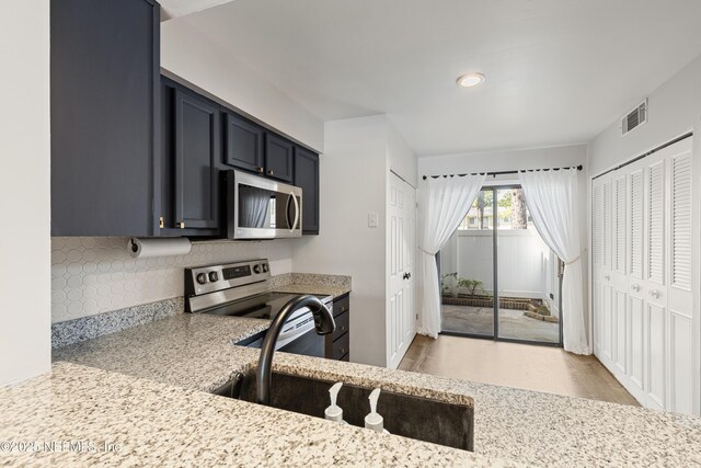 7855 La Sierra Ct Unit 7855, Jacksonville, FL 32256 - kitchen featuring appliances with stainless steel finishes, backsplash, light wood finished floors, light stone countertops, and recessed lighting