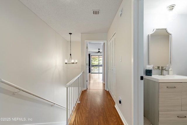 7855 La Sierra Ct Unit 7855, Jacksonville, FL 32256 - hallway with an upstairs landing, wood finished floors, a chandelier, and a textured ceiling