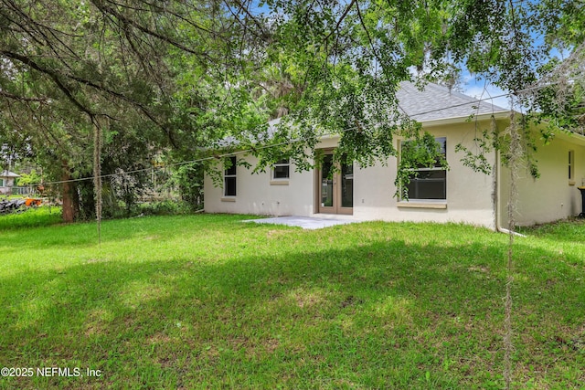 204 S Forsyth Ln, Bunnell, FL 32110 - back of house featuring stucco siding, a yard, roof with shingles, and a patio