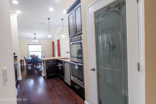 11115 Parkside Preserve Way, Jacksonville, FL 32257 - kitchen featuring ornamental molding, a peninsula, appliances with stainless steel finishes, dark wood finished floors, and pendant lighting