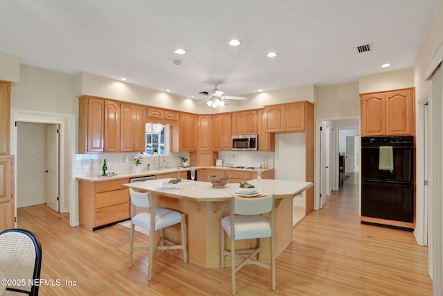 2785 Holly Point Rd E, Orange Park, FL 32073 - kitchen featuring stainless steel microwave, light wood-type flooring, a kitchen island, tasteful backsplash, and recessed lighting