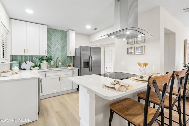 165 Sherry Dr, Atlantic Beach, FL 32233 - kitchen featuring island range hood, light wood-type flooring, white cabinetry, and a kitchen breakfast bar