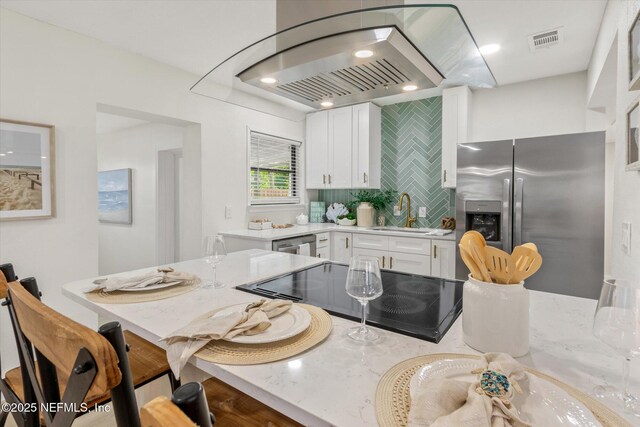 165 Sherry Dr, Atlantic Beach, FL 32233 - kitchen featuring stainless steel fridge with ice dispenser, black electric stovetop, white cabinetry, a breakfast bar area, and island exhaust hood
