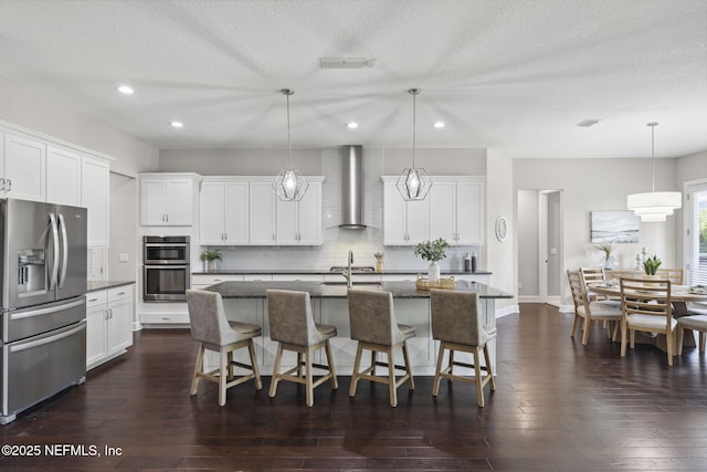 168 Bronson Pkwy, Saint Augustine, FL 32095 - kitchen featuring stainless steel appliances, wall chimney exhaust hood, recessed lighting, a breakfast bar area, and tasteful backsplash