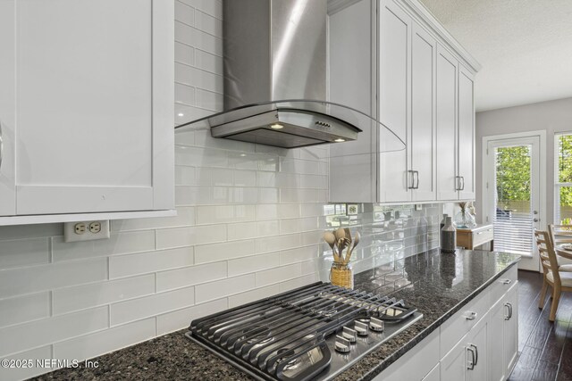 168 Bronson Pkwy, Saint Augustine, FL 32095 - kitchen featuring wall chimney exhaust hood, stainless steel gas stovetop, white cabinets, dark stone countertops, and decorative backsplash