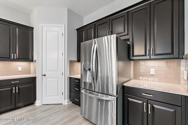 150 Calumet Dr, Saint Johns, FL 32259 - kitchen with stainless steel refrigerator with ice dispenser, backsplash, light wood finished floors, light stone counters, and a textured ceiling