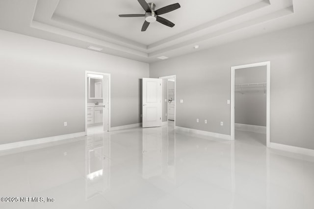 20 Evansville Ln, Palm Coast, FL 32164 - unfurnished bedroom with a tray ceiling, light tile patterned flooring, connected bathroom, and a spacious closet