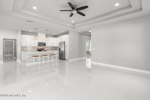 20 Evansville Ln, Palm Coast, FL 32164 - unfurnished living room with a tray ceiling, recessed lighting, ceiling fan, and light tile patterned floors
