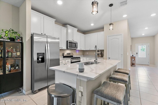 235 Brybar Dr, Saint Augustine, FL 32095 - kitchen featuring appliances with stainless steel finishes, light tile patterned floors, light stone counters, white cabinetry, and a breakfast bar area
