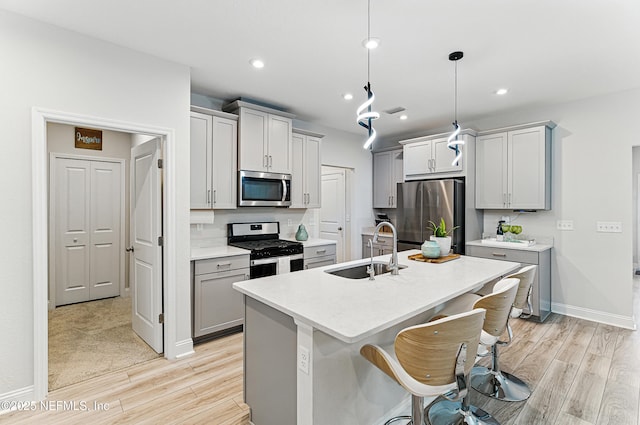 105 Meadow Creek Dr, Saint Johns, FL 32259 - kitchen featuring stainless steel appliances, light wood-type flooring, gray cabinets, a breakfast bar, and light countertops