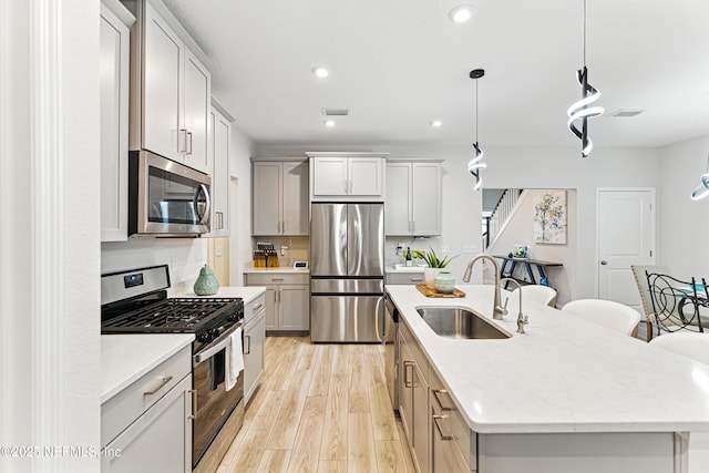 105 Meadow Creek Dr, Saint Johns, FL 32259 - kitchen featuring appliances with stainless steel finishes, an island with sink, light wood finished floors, hanging light fixtures, and recessed lighting
