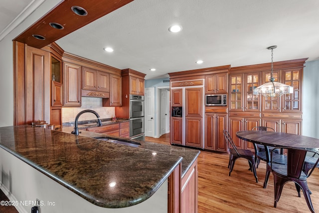3679 Rustic Ln, Jacksonville, FL 32217 - kitchen featuring built in appliances, brown cabinets, light wood-style flooring, a chandelier, and a peninsula