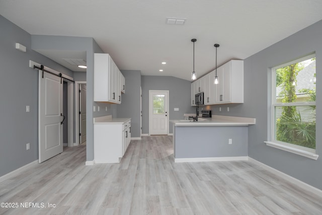 460 S Nassau St, Saint Augustine, FL 32084 - kitchen with stainless steel microwave, a barn door, light countertops, light wood-style flooring, and recessed lighting