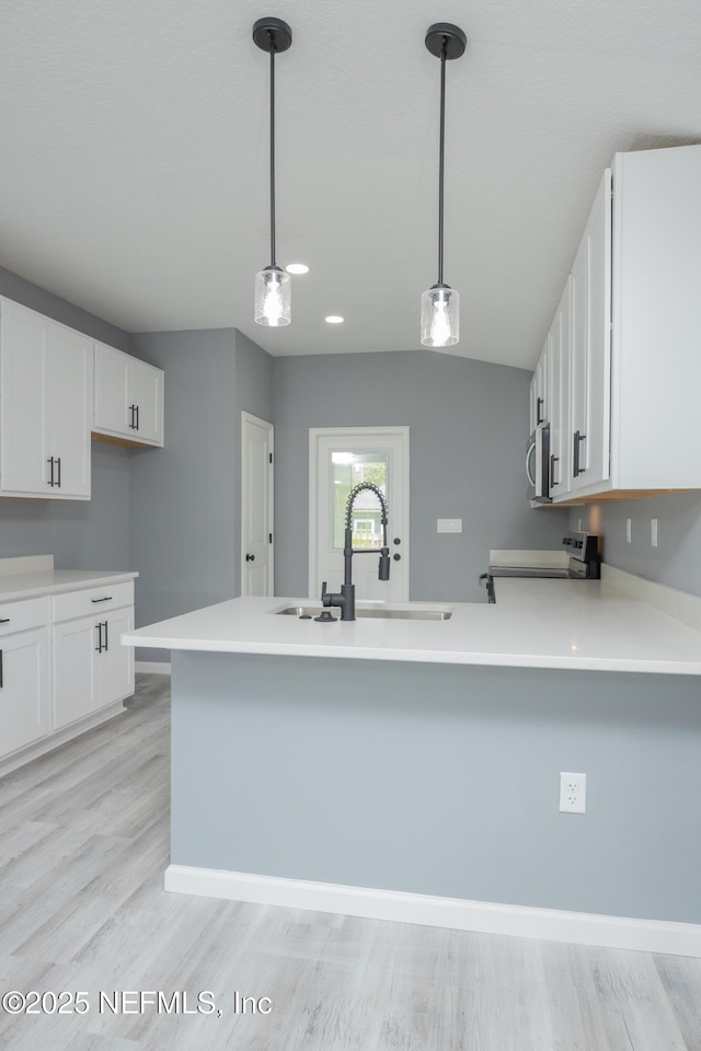 460 S Nassau St, Saint Augustine, FL 32084 - kitchen with stainless steel microwave, electric stove, white cabinets, light wood-style flooring, and a peninsula