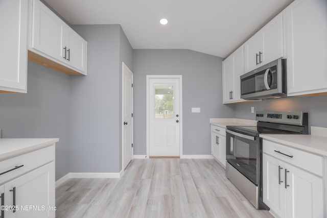 460 S Nassau St, Saint Augustine, FL 32084 - kitchen with appliances with stainless steel finishes, light wood finished floors, vaulted ceiling, light countertops, and white cabinets