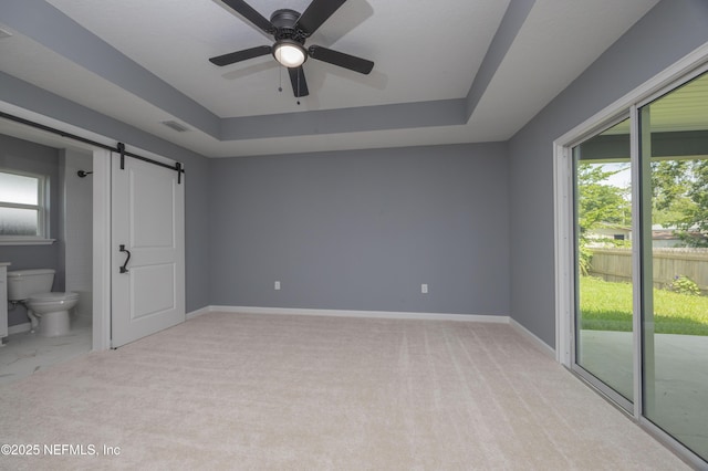 460 S Nassau St, Saint Augustine, FL 32084 - unfurnished bedroom featuring a barn door, access to exterior, a tray ceiling, ensuite bath, and light carpet