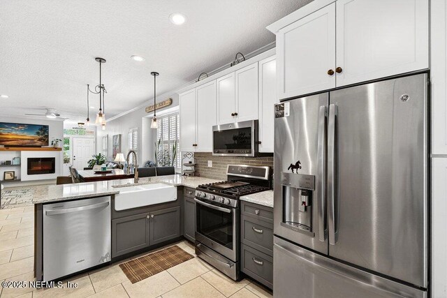611 Selva Lakes Cir, Atlantic Beach, FL 32233 - kitchen featuring stainless steel appliances, open floor plan, white cabinetry, a peninsula, and light stone counters