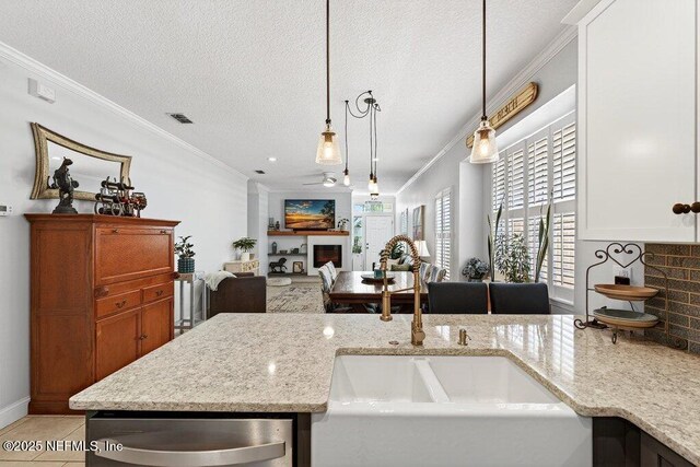 611 Selva Lakes Cir, Atlantic Beach, FL 32233 - kitchen featuring a fireplace, stainless steel dishwasher, ornamental molding, light stone countertops, and pendant lighting