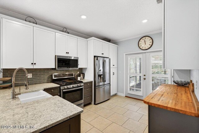 611 Selva Lakes Cir, Atlantic Beach, FL 32233 - kitchen with appliances with stainless steel finishes, ornamental molding, decorative backsplash, light tile patterned floors, and white cabinetry