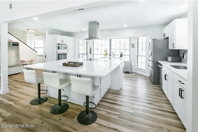 8820 Bandera Cir S, Jacksonville, FL 32244 - kitchen featuring island range hood, appliances with stainless steel finishes, light wood-style flooring, a center island, and recessed lighting