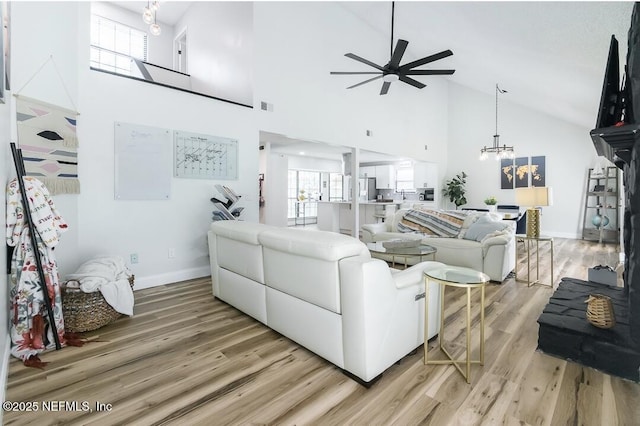 8820 Bandera Cir S, Jacksonville, FL 32244 - living room with high vaulted ceiling, a ceiling fan, light wood-style floors, a chandelier, and plenty of natural light