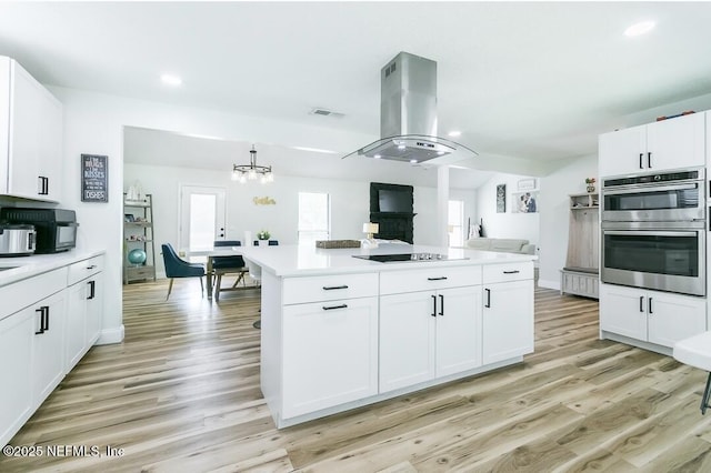 8820 Bandera Cir S, Jacksonville, FL 32244 - kitchen with island exhaust hood, stainless steel double oven, light countertops, light wood-style flooring, and recessed lighting