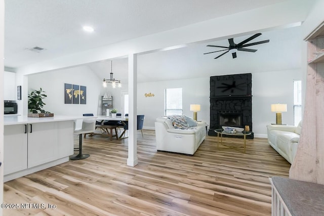8820 Bandera Cir S, Jacksonville, FL 32244 - living room with lofted ceiling, a fireplace, ceiling fan, light wood-style floors, and a chandelier