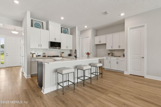 85448 Sandy Ridge Loop Unit 0049, Yulee, FL 32097 - kitchen with stainless steel microwave, decorative backsplash, a breakfast bar, light wood-type flooring, and recessed lighting