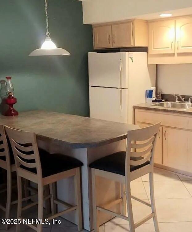 3700 Atlantic Ave Unit 405, New Smyrna Beach, FL 32169 - kitchen with freestanding refrigerator, a kitchen breakfast bar, pendant lighting, light tile patterned flooring, and white cabinetry