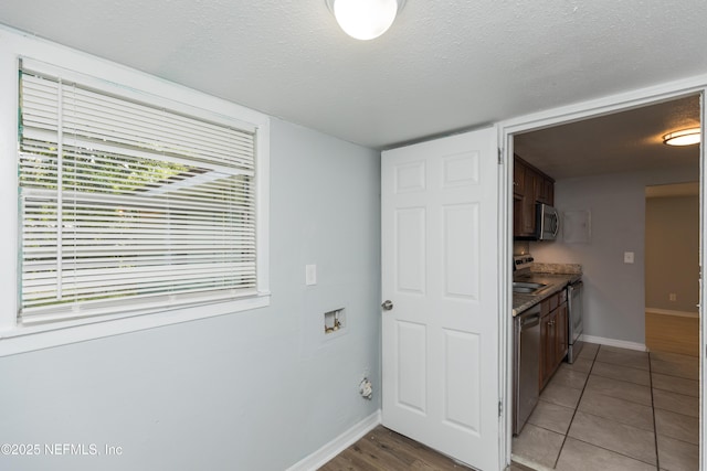 3303 Jones St, Jacksonville, FL 32206 - kitchen with appliances with stainless steel finishes, dark brown cabinets, light tile patterned floors, and a textured ceiling